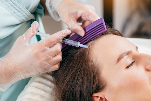 Young blonde woman with hair loss problem receiving injection, close up