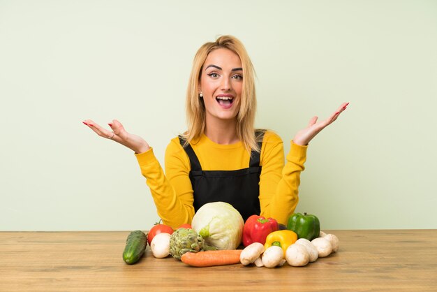 Young blonde woman with lots of vegetables unhappy and frustrated with something