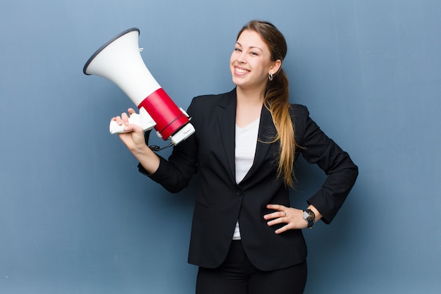 Young blonde woman with a megaphone against grunge wall