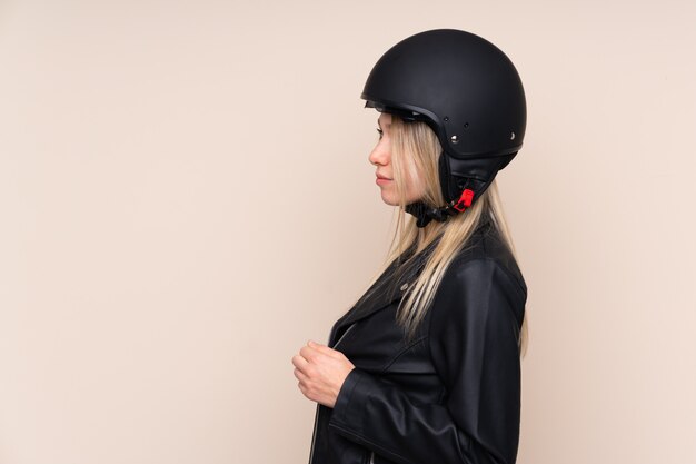 Foto giovane donna bionda con un casco del motociclo sopra la parete isolata