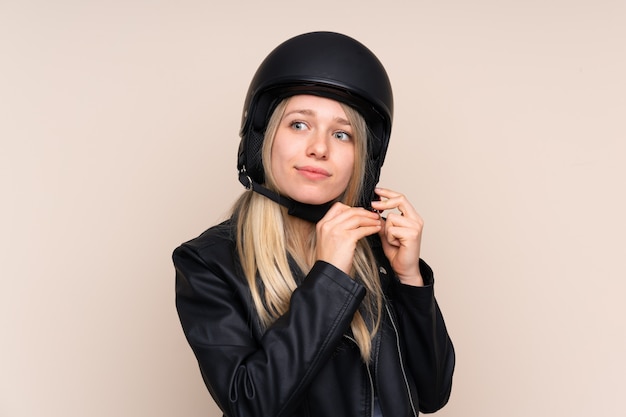 Young blonde woman with a motorcycle helmet over isolated wall