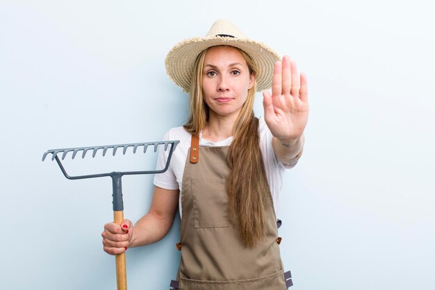 Young blonde woman with a rake farmer concept