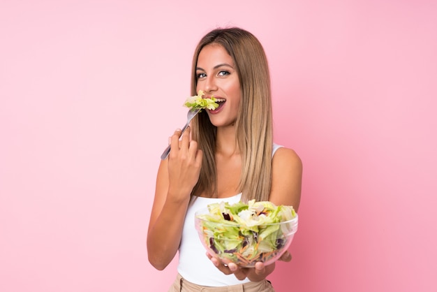 Young blonde woman with salad over isolated 