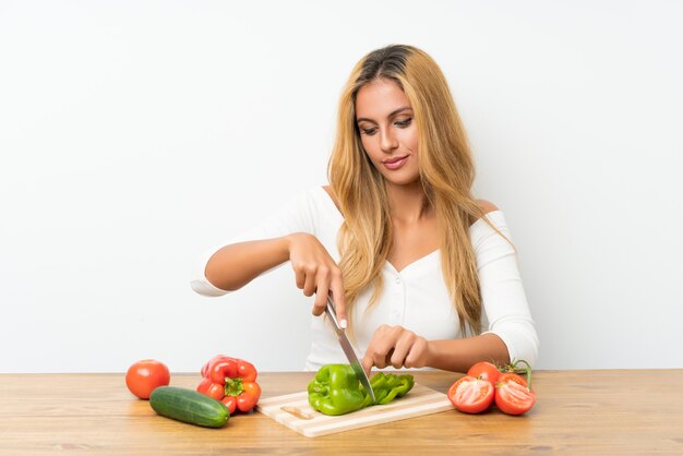 テーブルに野菜と若いブロンドの女性