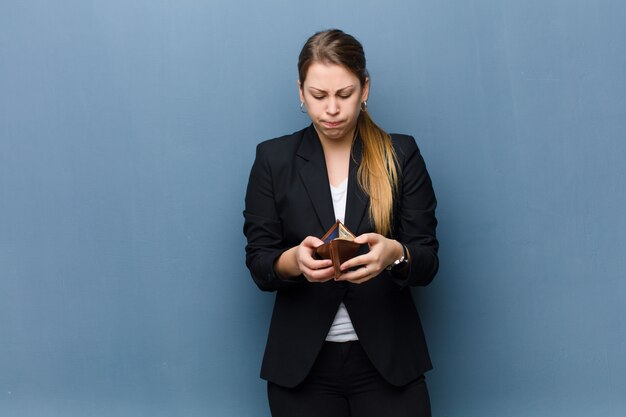 Young blonde woman with a wallet against grunge wall