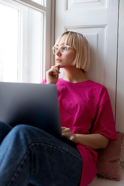 Giovane donna bionda che lavora da casa sul suo laptop