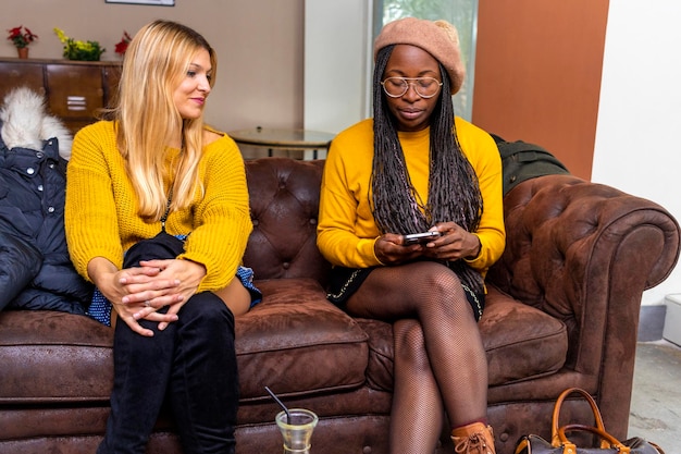 Young blonde woman and young black woman look at the phone