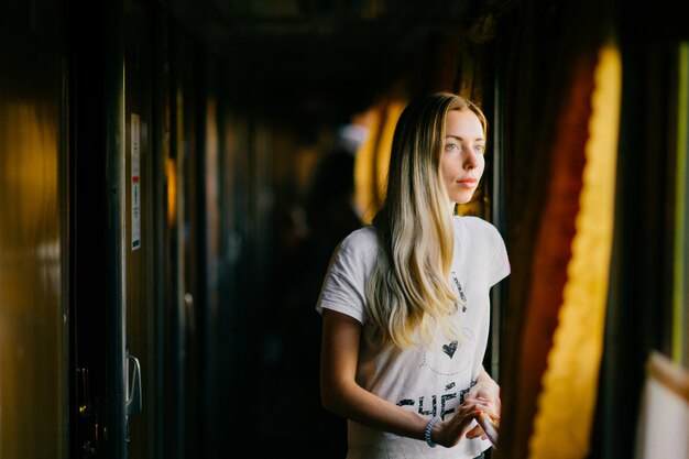 Молодая блондинка смотрит в окно в поезде