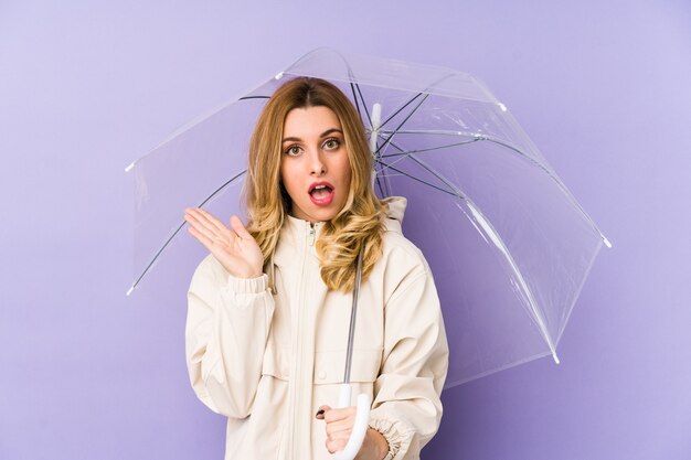 Young bloverde woman holding an umbrella isolated Young bloverde woman holding an umbrella isolated surprised and shocked.