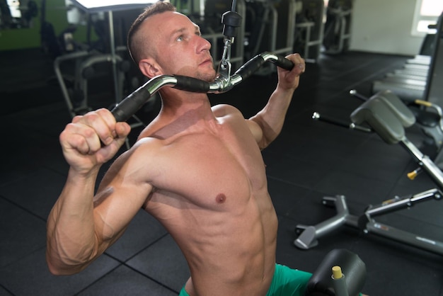 Photo young bodybuilder doing heavy weight exercise for back on machine