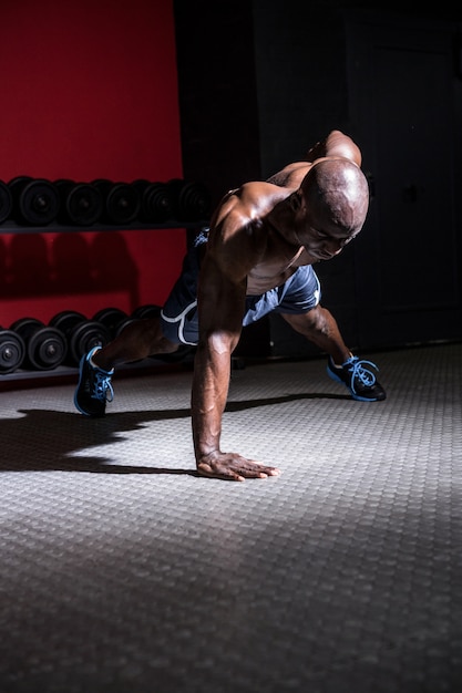 Young bodybuilder doing one-armed push ups