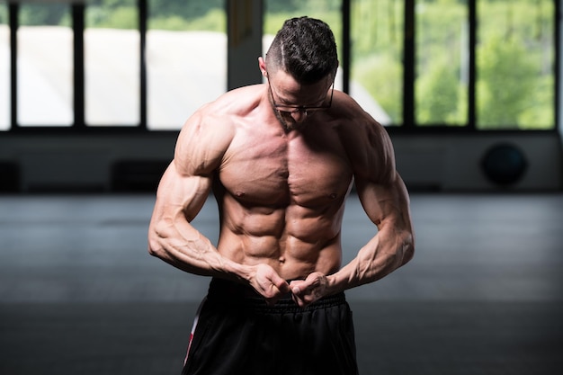 Young Bodybuilder Wearing Eyeglasses Flexing Muscles