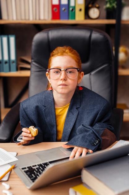 Photo young boss. nice serious girl looking at you while wearing a big suit