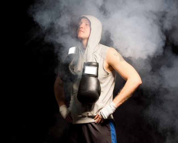 Young boxer standing in a smoky atmosphere breathing deeply to calm his nerves