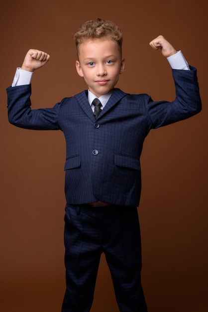 Young boy as businessman on brown wall