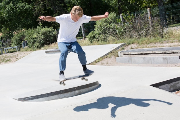 Young boy blonde teenager skating in skatepark