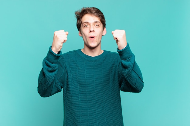 Young boy celebrating an unbelievable success like a winner, looking excited and happy saying take that!