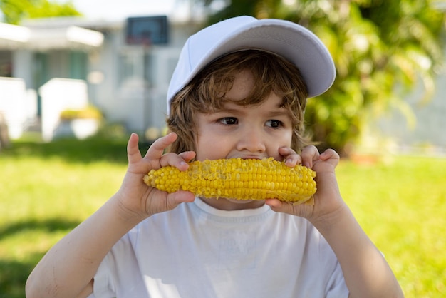 写真 穂軸農業と秋の作物でトウモロコシを食べる少年は、子供のための野菜や果物をコンセプトにしています