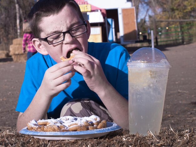 Young boy eating funnel cake.