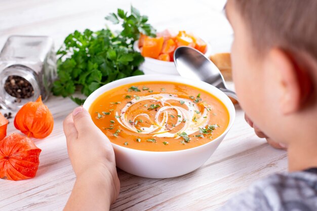 カボチャスープを食べる少年。離乳食の概念。