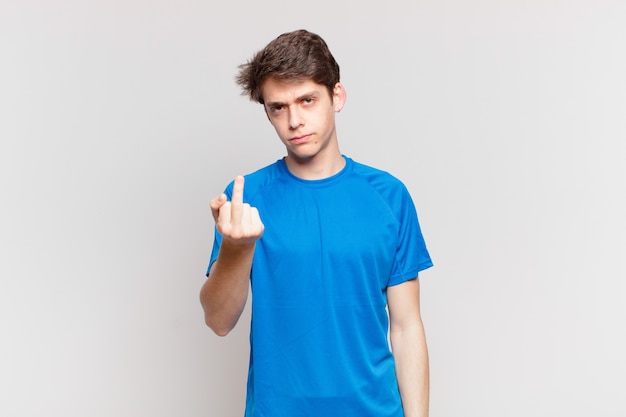 Young boy feeling angry, annoyed, rebellious and aggressive, flipping the middle finger, fighting back