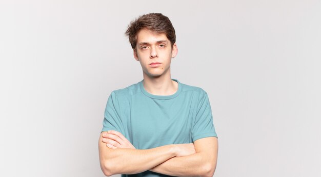 Young boy feeling displeased and disappointed, looking serious, annoyed and angry with crossed arms