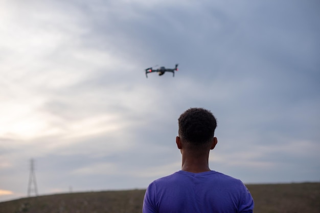 Young boy flying a drone seen from the rear