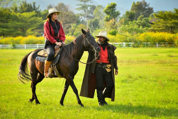 Ragazzo e ragazza cowboy equitazione sul prato mite sole al mattino
