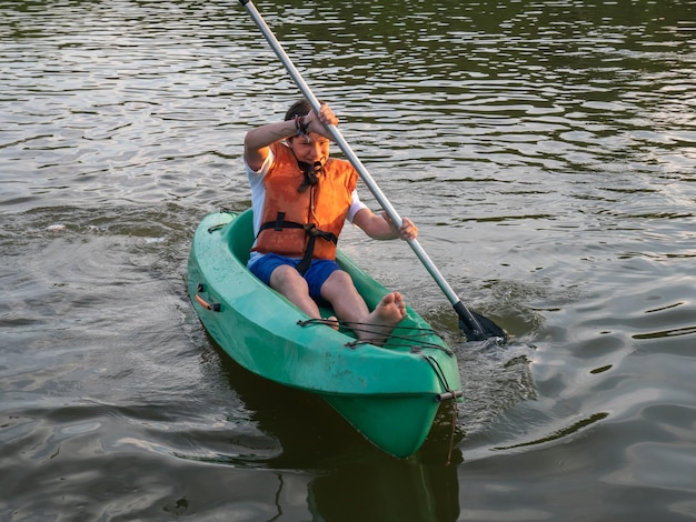 Young boy having fun kayaking on the lake at sunset