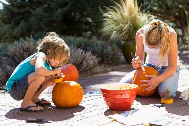 Young boy and his sister carving pumpkins