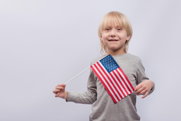 Young boy holding an American flag on white background Study of American English