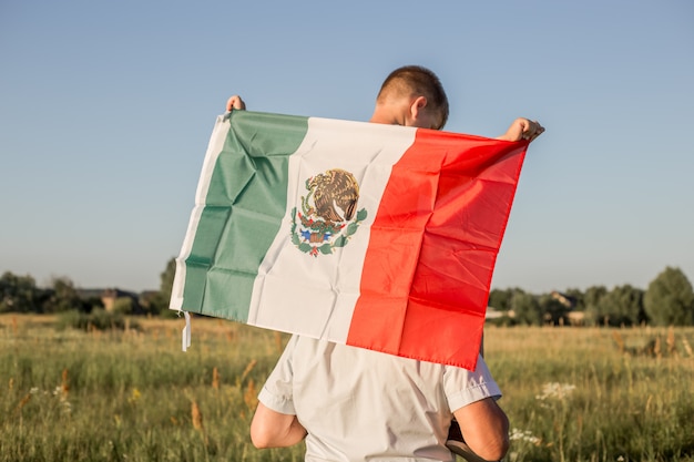 Young boy holding flag of mexico. 