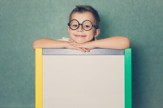 Young boy holding white blank board on blue