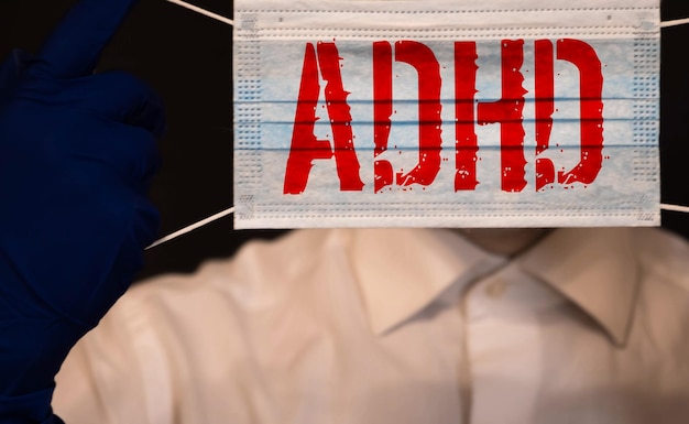 Photo young boy holds adhd text written on sheet of paper adhd is attention deficit hyperactivity disorder