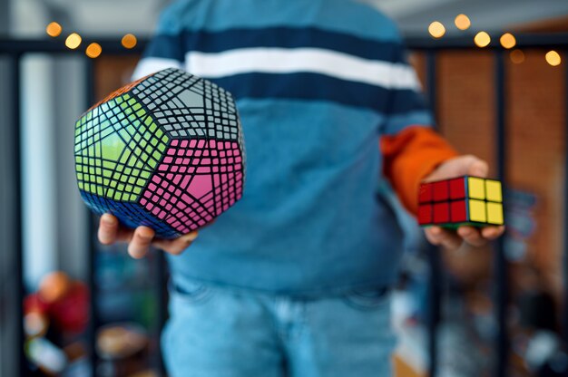 Young boy holds puzzle cubes in his hands. Toy for brain and logical mind training, creative game, solving of complex problems