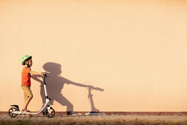 A young boy is riding a scooter in a protective helmet