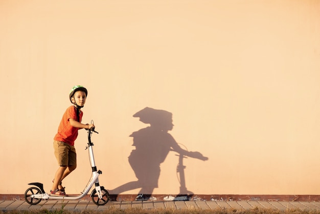 A young boy is riding a scooter in a protective helmet