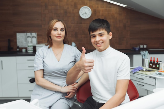 Young boy is satisfied with the visit to the dentist The concept of painless dental treatment Beautiful wide smile of a child Thumbs up