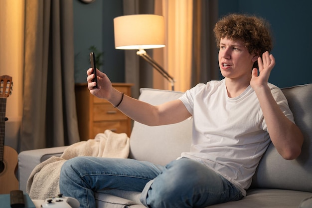 A young boy is sitting on the couch in the living room in the evening