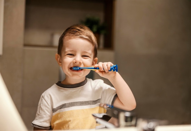 A young boy is standing in bathroom and bushing his teeth