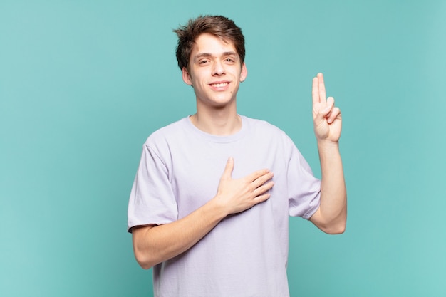 Young boy looking happy, confident and trustworthy, smiling and showing victory sign, with a positive attitude