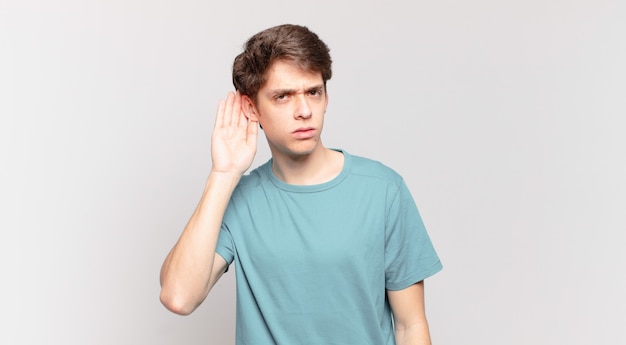 Young boy looking serious and curious, listening, trying to hear a secret conversation or gossip, eavesdropping