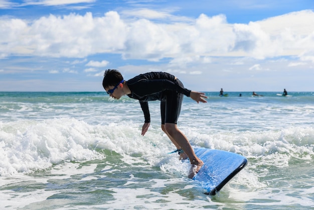 Photo young boy new student in surfing loses his body balance and falls from surfboard into the water during class