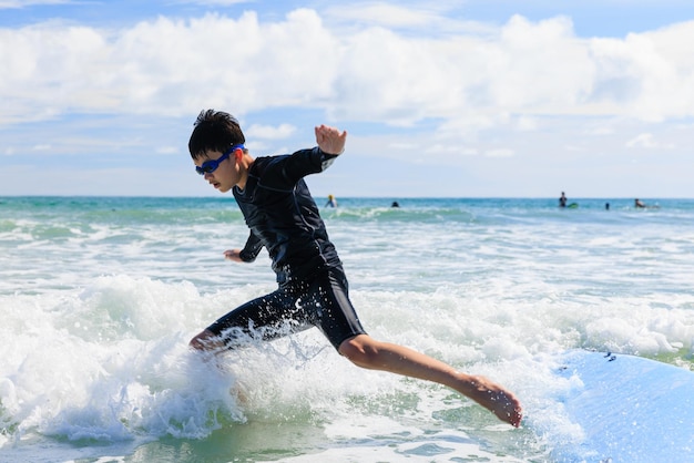 Foto ragazzo un nuovo studente di surf perde la presa e cade da una tavola da surf in acqua durante la lezione