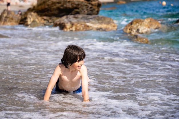 波の中で一人で遊んでいる少年。