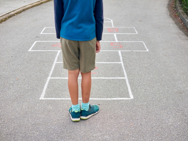 Young boy playing hopscotch outdoors