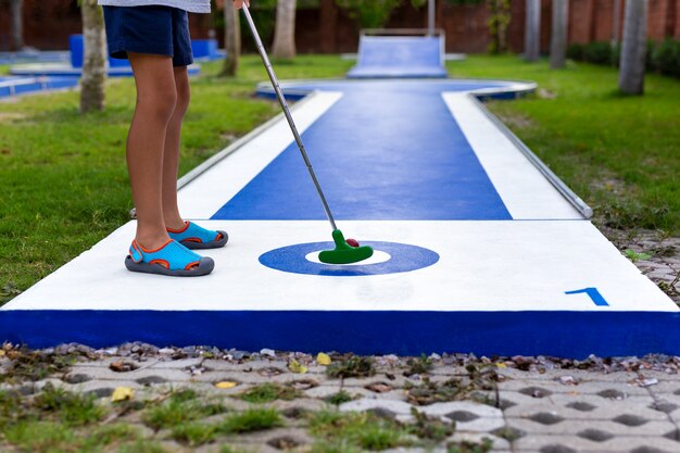 Photo young boy playing mini golf