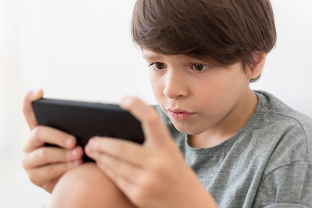 Photo young boy playing on smartphone