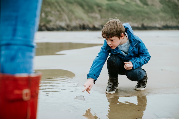 Молодой мальчик, указывая на медуз на берегу моря