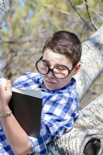 Young boy reading a book in the woods with shallow depth of field and copy space